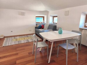A modern living room with a white table and chairs, a grey sofa, and a striped rug. - At Vale's House (Pescocostanzo)