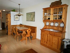 Ein Essbereich mit einem Holztisch und Stühlen, einer Vitrine mit Glastüren und einer hängenden Leuchte.