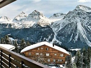 Eine Holzhütte mit schneebedecktem Dach, umgeben von verschneiten Bergen.