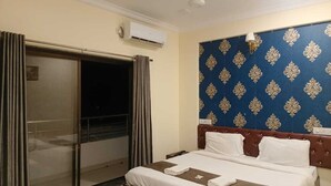 A hotel room with a bed, a wardrobe, and a patterned wall. - Varo Inn (Mahabaleshwar)