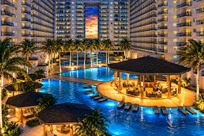 A multi-level hotel with a large indoor swimming pool, lounge areas, and a central bar. - Ritzy 1Br Condo Facing Mall Of Asia at Shell Residences (Pasay)