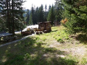 Uma cabana rústica com parede de pedra, deck de madeira e mesa de piquenique.