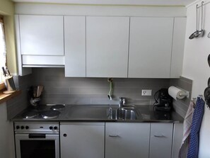 Una cocina con armarios blancos, una estufa y un lavabo.