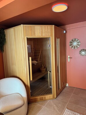 A sauna with a wooden exterior, a glass door, and a visible interior with a wooden bench and a towel.