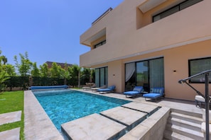 A modern outdoor swimming pool with lounge chairs and a staircase leading to a covered area. - Villa Yasmine – Luxury villa with pools, hammam, and gym in Marrakech (Douar Moulay Abbas)