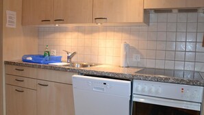 Una cucina con mobili in legno, lavastoviglie integrata, piano cottura e lavello.
