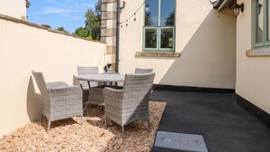 Eine Terrasse mit Korbmöbeln, einem Tisch und Stühlen.