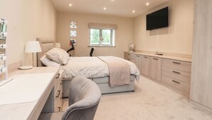Ein Schlafzimmer mit Bett, Schreibtisch, Stuhl, Schminktisch, Spiegel, Fernseher und Fenster.