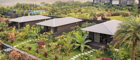 A modern resort with multiple bungalow-style buildings surrounded by lush gardens and palm trees.