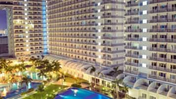Un hotel de varios pisos con piscina y palmeras.
