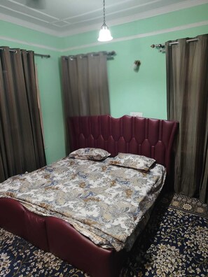 Una habitación con cama, cortinas y una lámpara colgante.