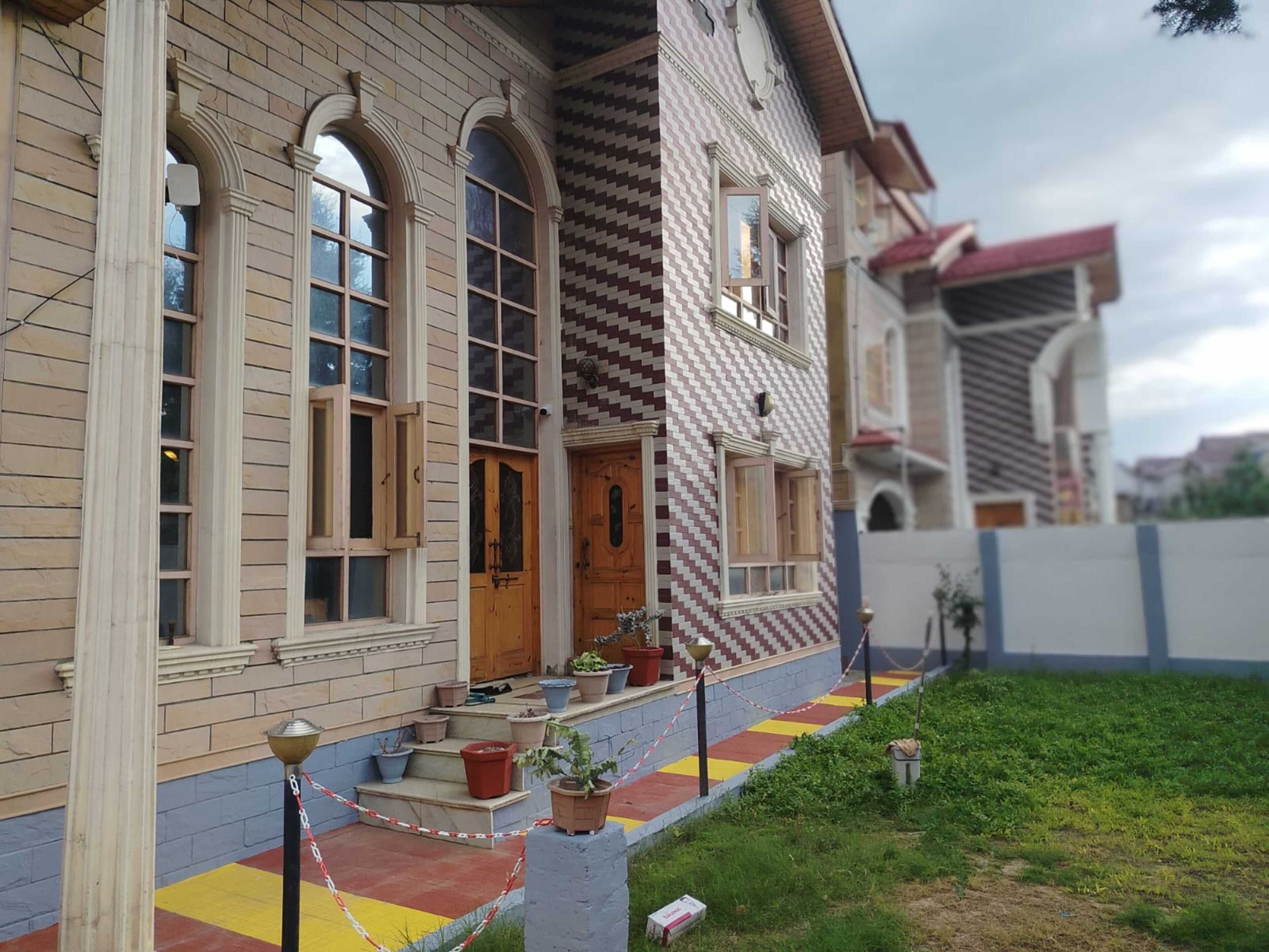 Un edificio de dos pisos con estilo arquitectónico tradicional, que presenta una puerta de madera y varios ventanales.