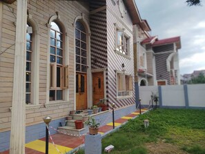 Un edificio de dos pisos con estilo arquitectónico tradicional, que presenta una puerta de madera y varios ventanales.