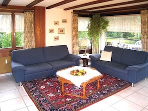 Ein Zimmer mit zwei Sofas, einem Tisch mit Obst und einem gemusterten Teppich.