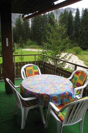 Ein überdachter Außenbereich mit Tisch und Stühlen mit Blick auf eine gebirgige Landschaft.