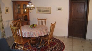 A dining area with a round table, chairs, a chandelier, a wooden cabinet, and a door. - Casa Laghetto 5 Appartement/Fewo, Bad, WC, 4-Bettwohnung 4-Bettwohnung by Interhome (Arosa)