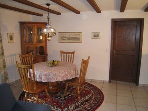 Ein Essbereich mit einem runden Tisch, Stühlen, einer Chandelier, einem Holzschrank und einer Tür.