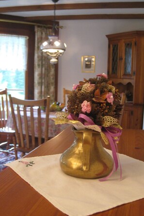 A brass vase with a floral arrangement on a table in a dining area. - Casa Laghetto 5 Appartement/Fewo, Bad, WC, 4-Bettwohnung 4-Bettwohnung by Interhome (Arosa)