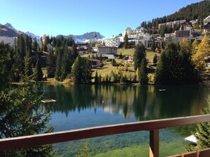 A lake with a reflection, surrounded by trees and buildings, with mountains in the background. - Casa Laghetto 5 Appartement/Fewo, Bad, WC, 4-Bettwohnung 4-Bettwohnung by Interhome (Arosa)
