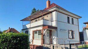 A two-story building with a flat roof, a visible entrance, and a sign indicating it is a holiday home. - HarzVilla (Bad Sachsa)