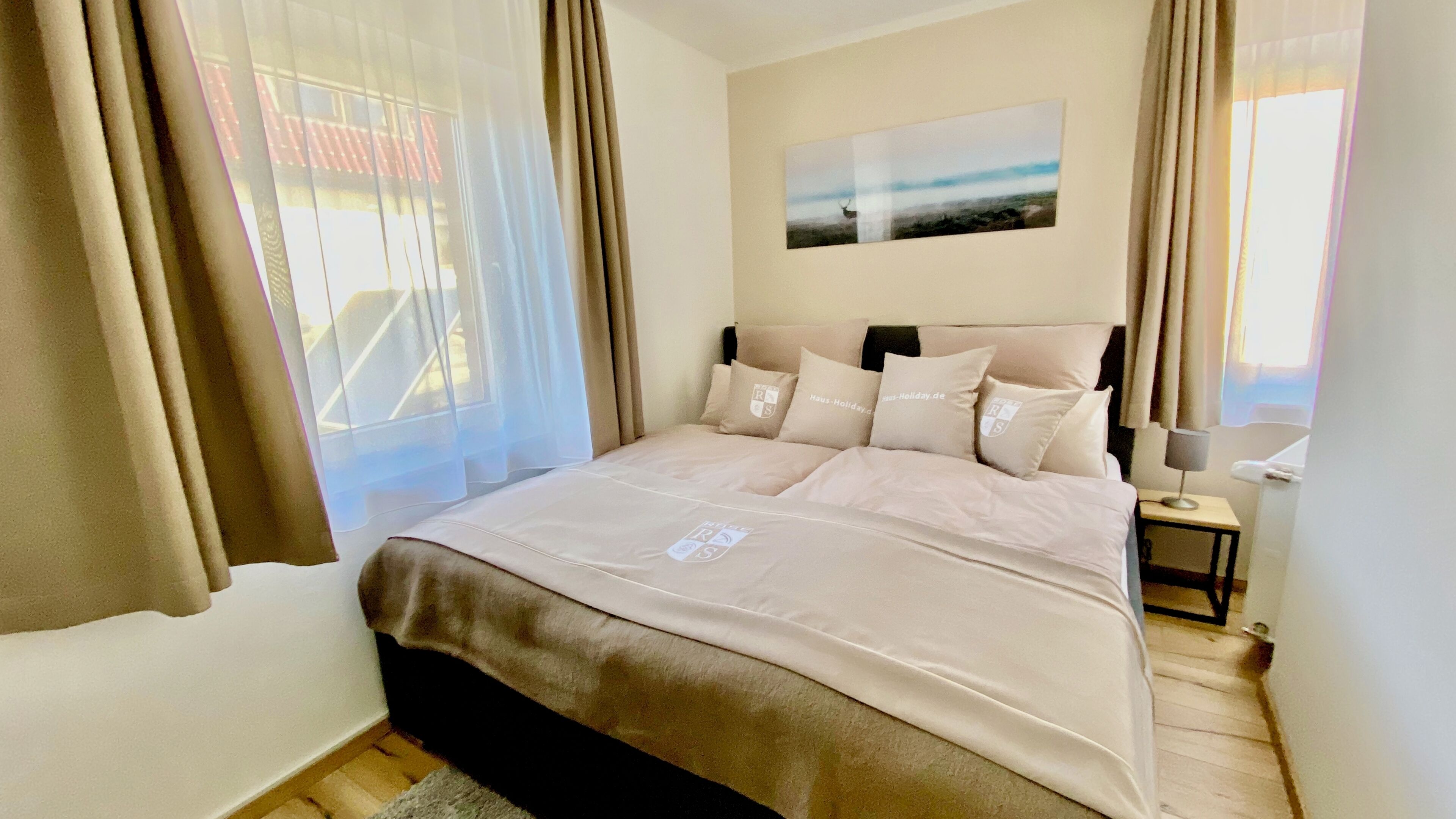 A bedroom with a bed, a nightstand, a lamp, and a window with curtains.
