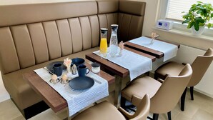 A dining area with a brown leather bench, a wooden table with a white tablecloth, and two chairs. - HarzVilla (Bad Sachsa)