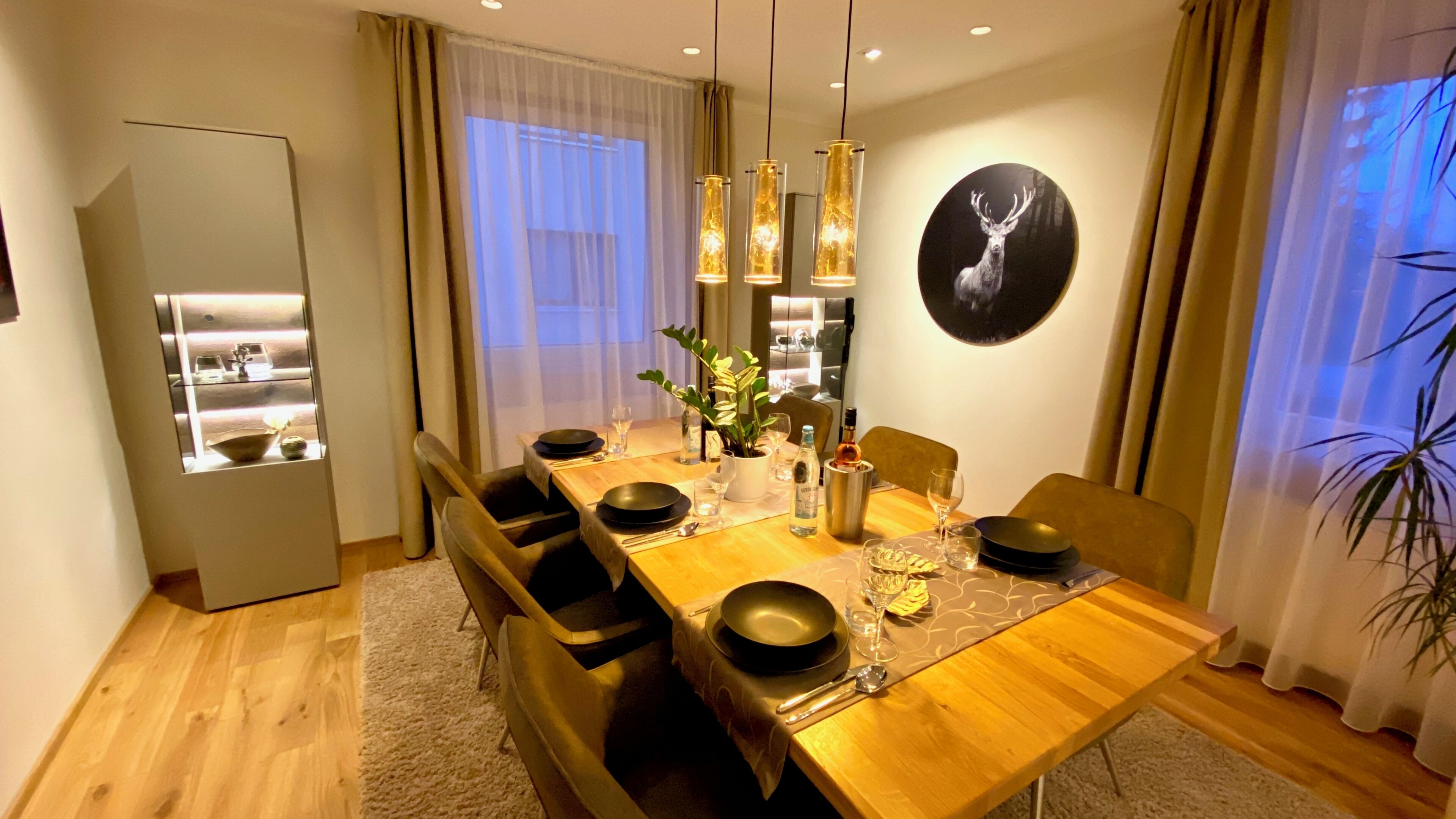 A dining area with a wooden table set for six, surrounded by chairs.