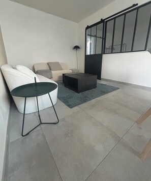 Una sala de estar moderna con un sofá, una mesita redonda y un reposapiés oscuro.