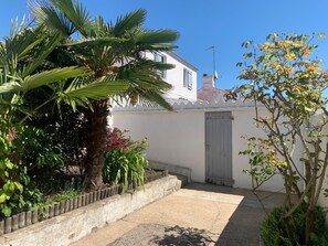 Propiedad residencial con patio empedrado, una palmera y un edificio blanco con puerta gris.