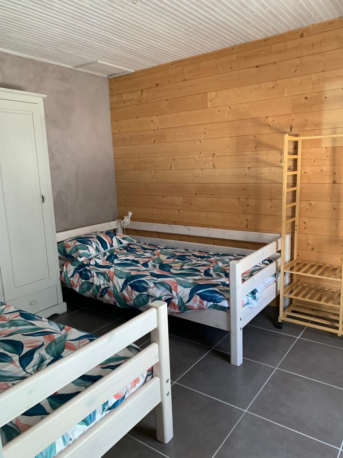 Ein Schlafzimmer mit zwei Einzelbetten, einem Holzschrank und einer Holzleiter.