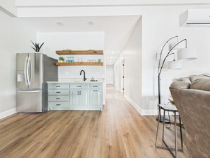 Une cuisine moderne avec un réfrigérateur en acier inoxydable, des armoires bleu clair et des étagères en bois.
