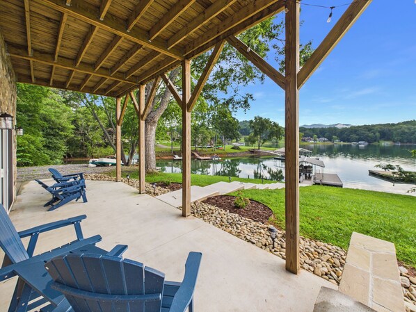 Un espace extérieur abrité, doté de fauteuils Adirondack, offrant une vue sur un lac et comprenant un quai pour bateaux.