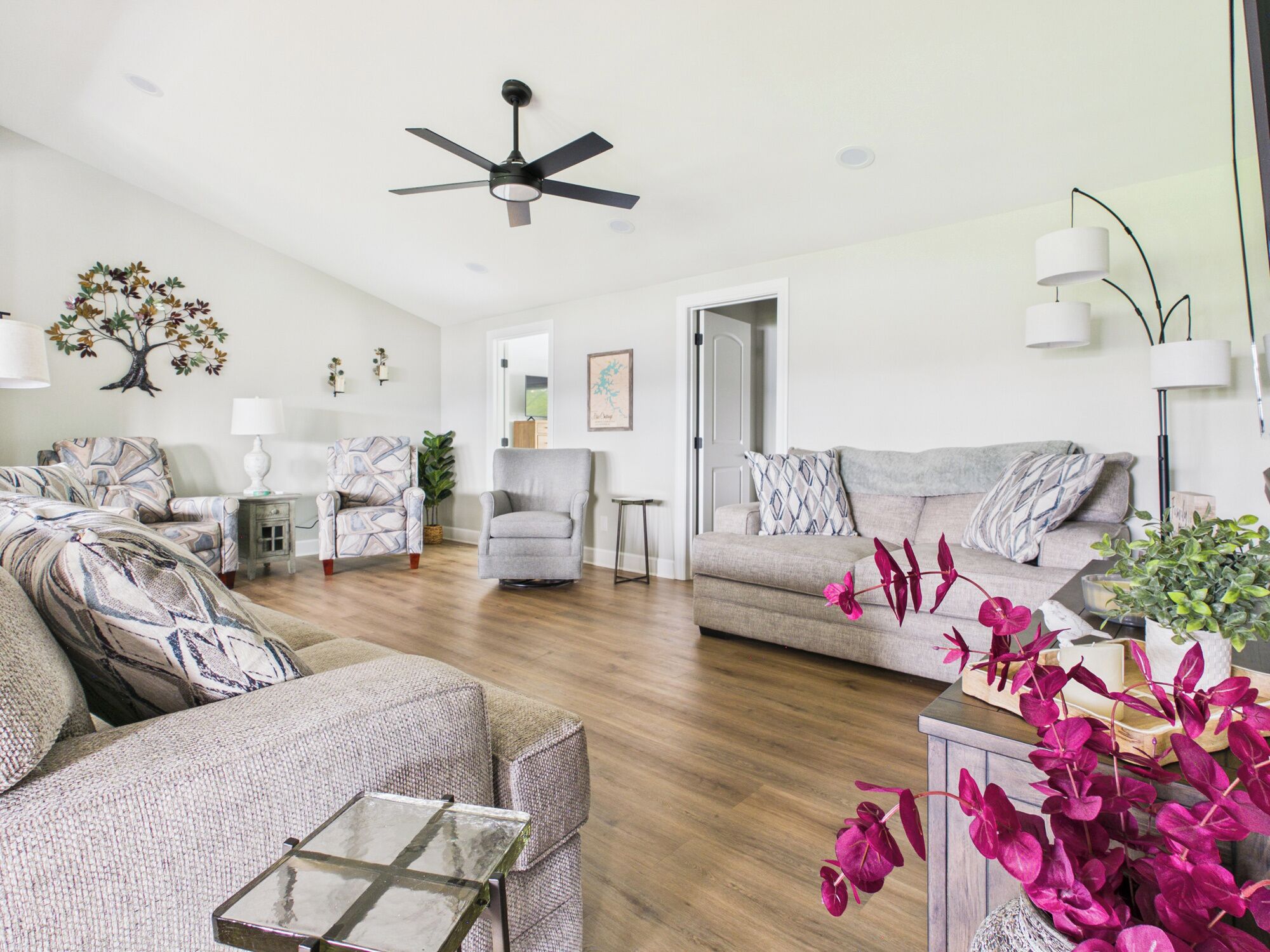 A spacious living room with a ceiling fan, a large window, and a door leading to another room.