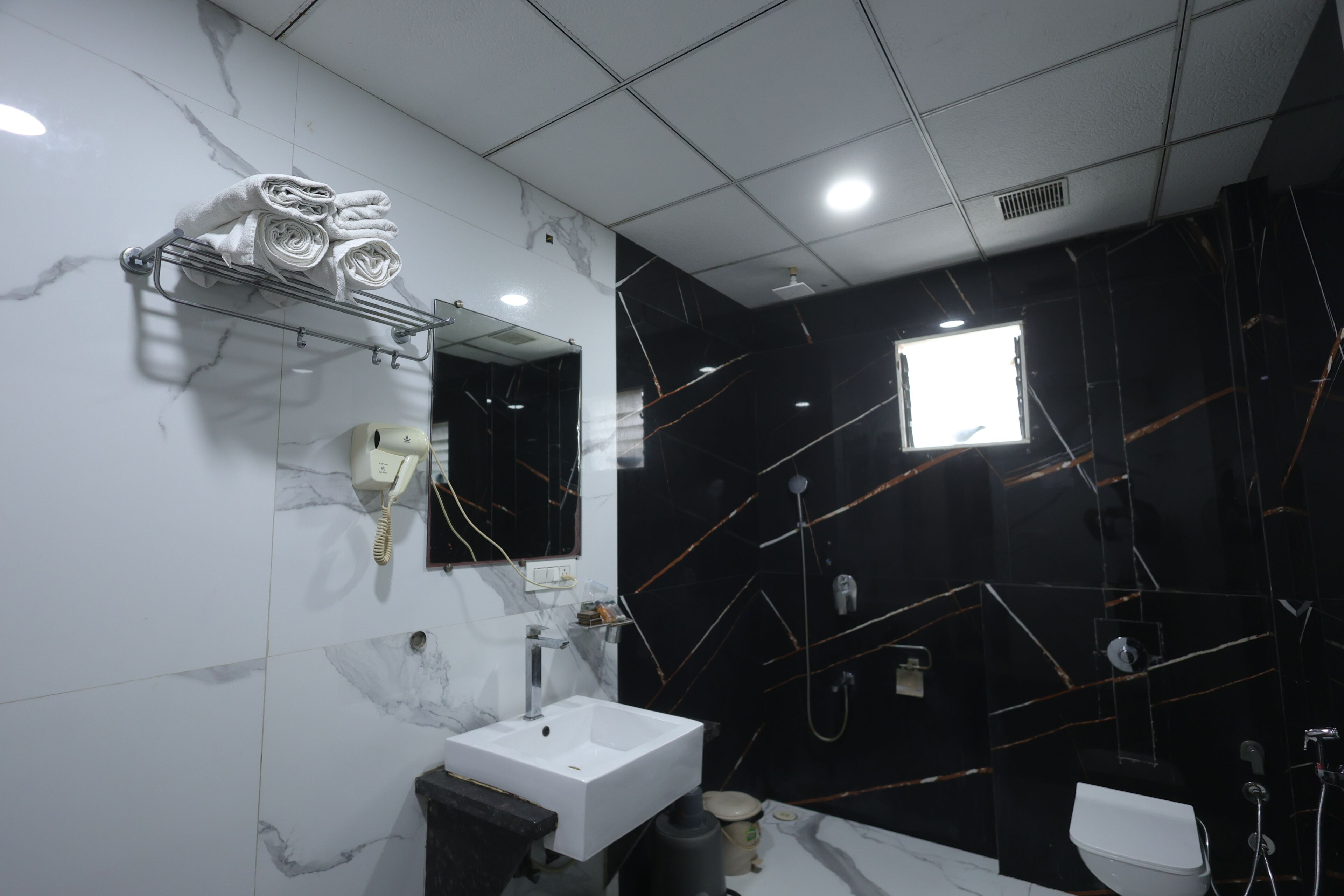 Un baño moderno con un lavabo blanco, un espejo y un perchero para toallas.