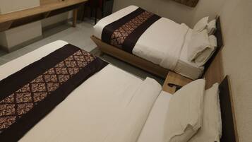 Una habitación de hotel con dos camas, un escritorio, una silla, un televisor y un espejo.