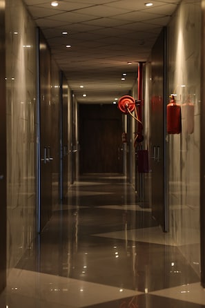 A corridor with reflective floors, glass doors, and emergency equipment.