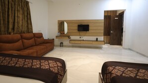 Une chambre d’hôtel moderne équipée d’un canapé, d’un lit, d’une télévision et d’une coiffeuse en bois.
