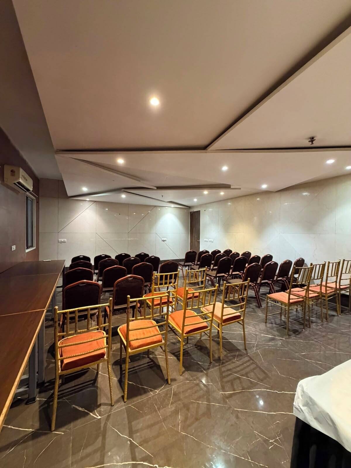 Un salón de conferencias con filas de sillas, una mesa larga y un diseño moderno en el techo.