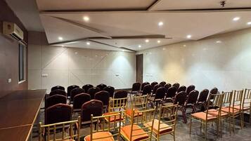 Un salón de conferencias con filas de sillas, una mesa larga y un diseño moderno en el techo.