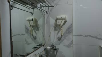 Un baño con lavamanos blanco, espejo, toallero y secador de pelo.