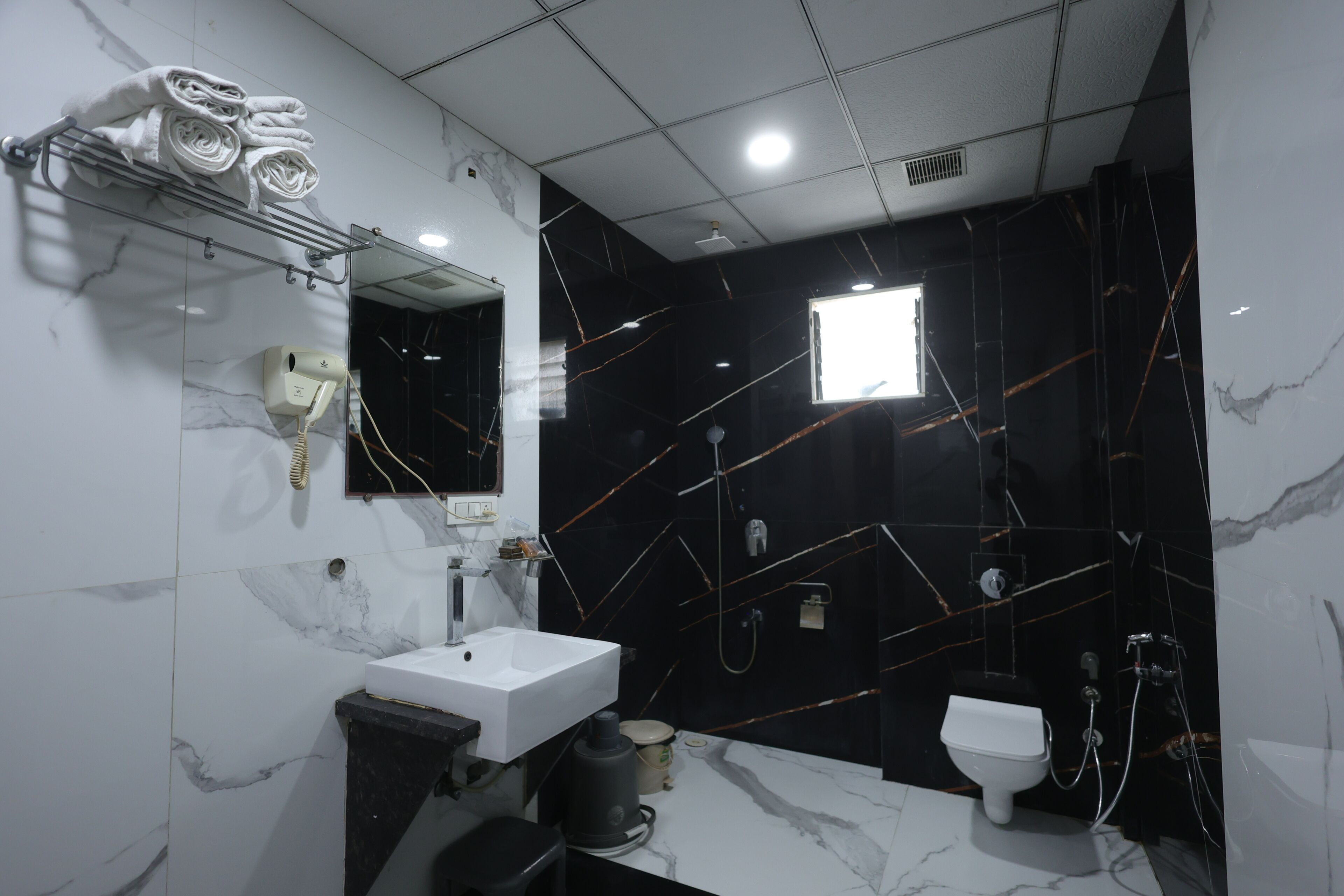 Um banheiro moderno com uma pia branca, um espelho, um secador de cabelo e um vaso sanitário.