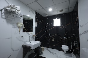 Un baño moderno con un lavamanos blanco, un espejo, un secador de pelo y un inodoro.
