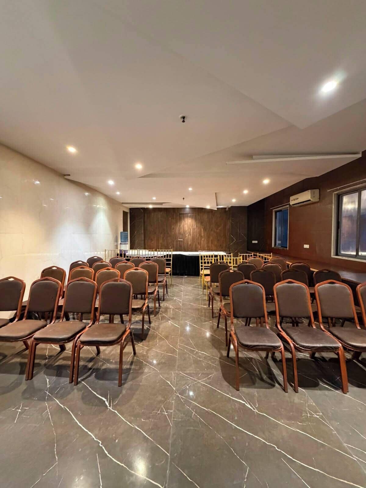 A conference room with rows of chairs, a podium, and a marble floor.