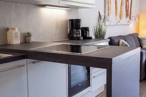 A modern kitchen with a built-in island, a coffee maker, and a Siemens oven. - Dünenvilla 10, Apartment 02 (Lübeck-Travemünde)