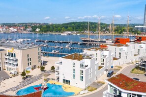 Eine Marina mit Booten, ein modernes Gebäude mit Dachgarten und Blick auf den Hafen.