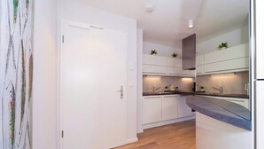 Uma cozinha moderna com armários brancos, forno embutido e bancada.