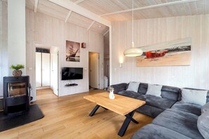 A modern living room with a sofa, a wooden coffee table, a TV, and a fireplace. - Fresh Breeze Vacation Home 23 (Lübeck-Travemünde)