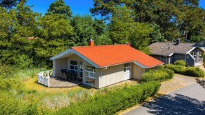 A small house with a red roof, a deck, and a fenced outdoor area. - Fresh Breeze Vacation Home 23 (Lübeck-Travemünde)