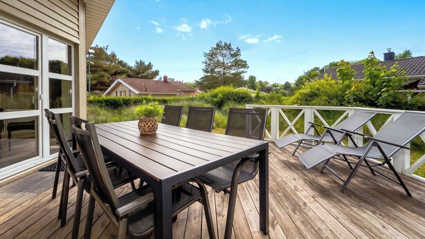 A wooden deck with a table and chairs, overlooking a residential area with houses and greenery. - Fresh Breeze Vacation Home 23 (Lübeck-Travemünde)