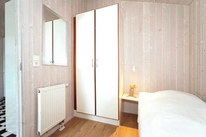 A bedroom with a wardrobe, a bedside table with a lamp, and a radiator. - Fresh Breeze Vacation Home 23 (Lübeck-Travemünde)